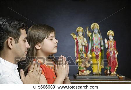 Mid adult man with his daughter praying in front of statues of God View Large Photo Image Stock Photo - Mid adult man with his daughter praying in front of statues of God. Fotosearch