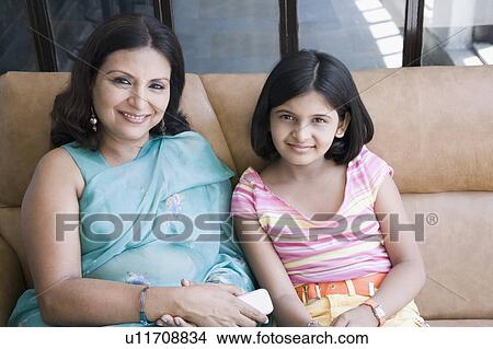 Portrait of a mature woman with her daughter sitting on a couch and smiling View Large Photo Image Picture - Portrait of a mature woman with her daughter sitting on a couch and smiling. Fotosearch