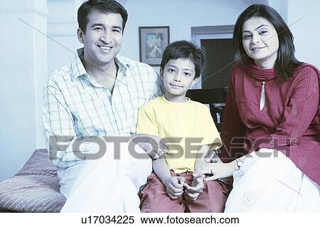 Stock Photography - Portrait of a mid adult couple sitting with their son and smiling. Fotosearch