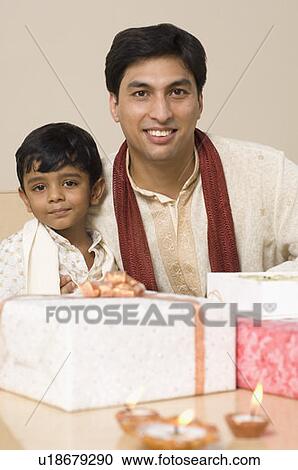 Portrait of a young man sitting with his son behind diwali gifts View Large Photo Image Stock Image - Portrait of a young man sitting with his son behind diwali gifts. Fotosearch