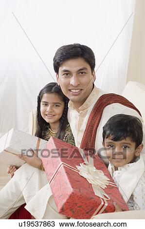 Portrait of a young man sitting with his son and daughter and holding diwali gifts View Large Photo Image Stock Image - Portrait of a young man sitting with his son and daughter and holding diwali gifts. Fotosearch