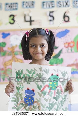 Stock Image - Portrait of a girl showing a drawing and smiling. Fotosearch