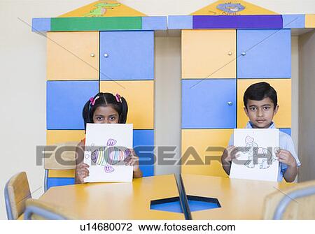 Portrait of a schoolboy and a schoolgirl showing paintings in a classroom View Large Photo Image Stock Image - Portrait of a schoolboy and a schoolgirl showing paintings in a classroom. Fotosearch