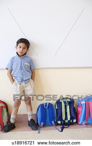 Portrait of a schoolboy standing beside schoolbags in a classroom View Large Photo Image Stock Image - Portrait of a schoolboy standing beside schoolbags in a classroom. Fotosearch