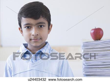 Portrait of a schoolboy with an apple on a stack of books behind him View Large Photo Image Stock Image - Portrait of a schoolboy with an apple on a stack of books behind him. Fotosearch