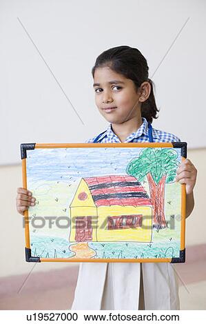 Stock Image - Portrait of a schoolgirl holding a painting and smiling. Fotosearch