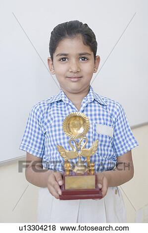Portrait of a schoolgirl holding a trophy View Large Photo Image Stock Photo - Portrait of a schoolgirl holding a trophy. Fotosearch