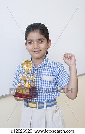 Portrait of a schoolgirl holding a trophy and smiling View Large Photo Image Stock Photograph - Portrait of a schoolgirl holding a trophy and smiling. Fotosearch