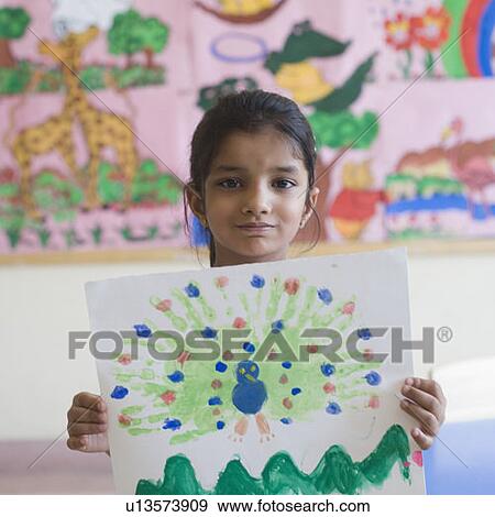 Stock Photo - Portrait of a schoolgirl showing a painting. Fotosearch