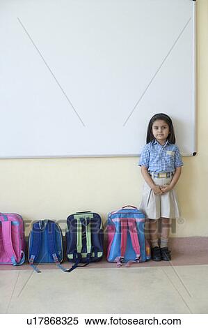 Portrait of a schoolgirl standing near schoolbags in a classroom View Large Photo Image Stock Photography - Portrait of a schoolgirl standing near schoolbags in a classroom. Fotosearch