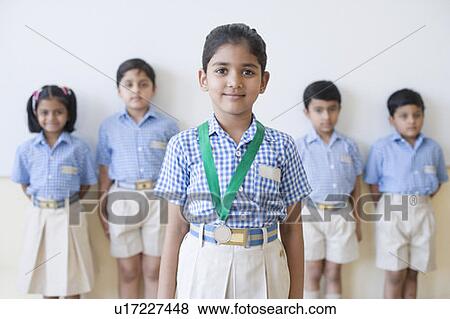 Stock Photo - Portrait of a schoolgirl with a medal around her neck with her classmates in the background. Fotosearch