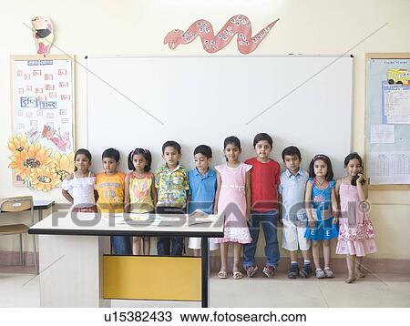 Stock Image - Schoolboys and schoolgirls standing side by side in a classroom. Fotosearch