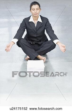 Businesswoman doing yoga in front of a stack of papers View Large Photo Image Stock Image - Businesswoman doing yoga in front of a stack of papers. Fotosearch