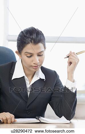 Businesswoman looking at a notebook in an office View Large Photo Image Stock Image - Businesswoman looking at a notebook in an office. Fotosearch