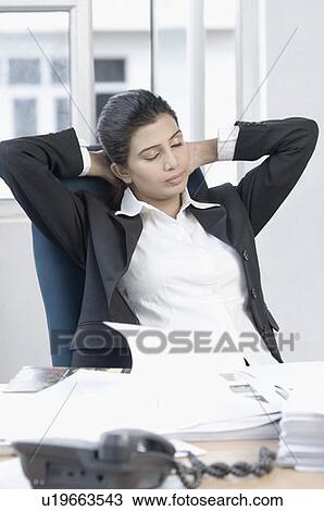 Businesswoman sitting in an office with her hands behind her head View Large Photo Image Stock Image - Businesswoman sitting in an office with her hands behind her head. Fotosearch