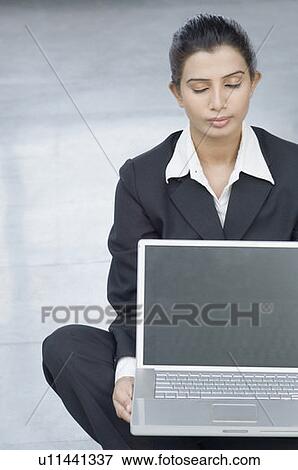 Close-up of a businesswoman holding a laptop and doing yoga View Large Photo Image Stock Photo - Close-up of a businesswoman holding a laptop and doing yoga. Fotosearch