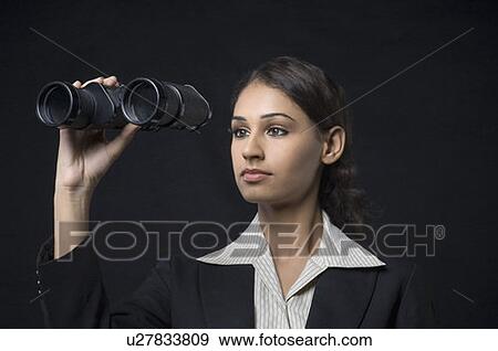 Close-up of a businesswoman holding binoculars in front of her face View Large Photo Image Stock Photo - Close-up of a businesswoman holding binoculars in front of her face. Fotosearch