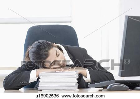 Stock Photograph - Close-up of a businesswoman leaning on a stack of papers and sleeping. Fotosearch