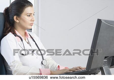 Close-up of a female doctor working on a computer View Large Photo Image Stock Photograph - Close-up of a female doctor working on a computer. Fotosearch