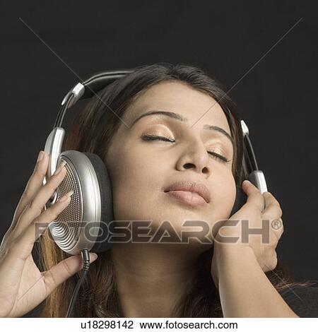 Stock Image - Close-up of a young woman listening to music. Fotosearch