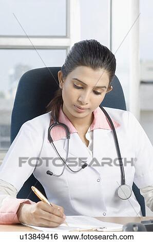 Stock Photograph - Female doctor sitting on a chair and holding a pen. Fotosearch