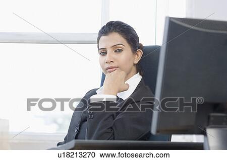 Portrait of a businesswoman sitting with her hand on her chin in an office View Large Photo Image Stock Image - Portrait of a businesswoman sitting with her hand on her chin in an office. Fotosearch