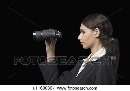 Stock Photo - Side profile of a businesswoman looking through a pair of binoculars. Fotosearch