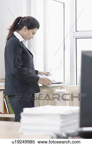 Side profile of a businesswoman standing and reading a book View Large Photo Image Stock Photography - Side profile of a businesswoman standing and reading a book. Fotosearch