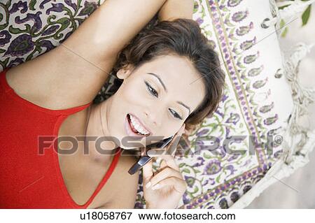 Close-up of a young woman lying in a hammock and using a mobile phone View Large Photo Image Stock Photo - Close-up of a young woman lying in a hammock and using a mobile phone. Fotosearch