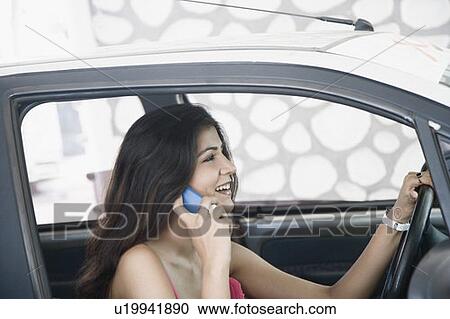 Close-up of a young woman sitting in a car and talking on a mobile phone View Large Photo Image Stock Image - Close-up of a young woman sitting in a car and talking on a mobile phone. Fotosearch