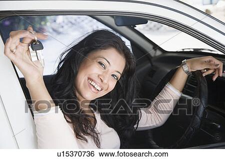 Stock Photograph - Portrait of a young woman holding a car key and laughing. Fotosearch