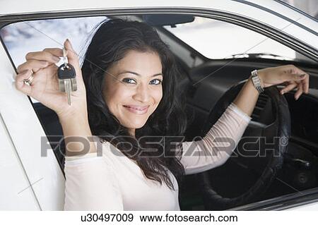 Portrait of a young woman sitting in a car and showing a car key View Large Photo Image Stock Photo - Portrait of a young woman sitting in a car and showing a car key. Fotosearch