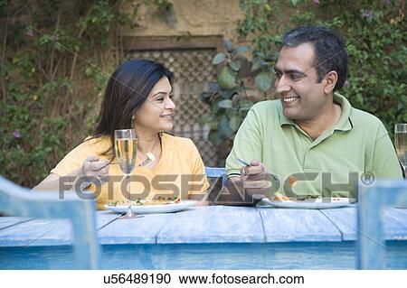 Stock Image - Close-up of a mid adult couple sitting at a dining table and smiling. Fotosearch