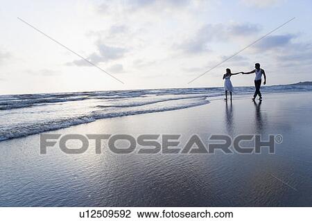 Stock Image - Couple walking on the beach. Fotosearch