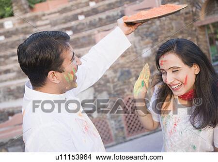 Picture - Mid adult couple celebrating holi. Fotosearch