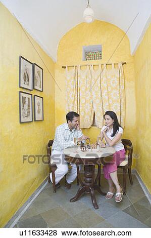 Stock Photo - Mid adult couple playing chess at a table. Fotosearch