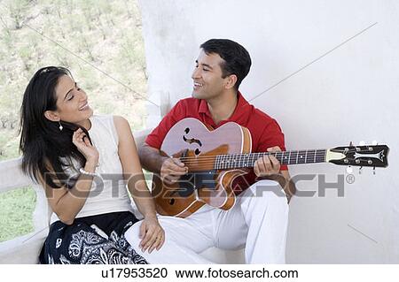 Stock Image - Mid adult couple sitting at the balcony of a palace, Neemrana Fort Palace, Neemrana, Alwar, Rajasthan, India. Fotosearch