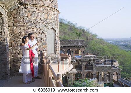 Stock Photo - Mid adult couple standing on the balcony of a fort, Neemrana Fort Palace, Neemrana, Alwar, Rajasthan, India. Fotosearch