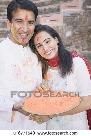 Stock Image - Portrait of a mid adult couple holding a plate of powder paint and smiling. Fotosearch