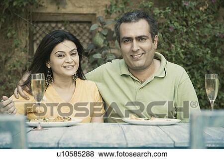Stock Photo - Portrait of a mid adult man arm around a mid adult woman and smiling. Fotosearch