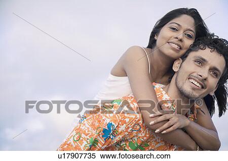 Portrait of a young woman riding piggyback on a young man and smiling View Large Photo Image Stock Photography - Portrait of a young woman riding piggyback on a young man and smiling. Fotosearch