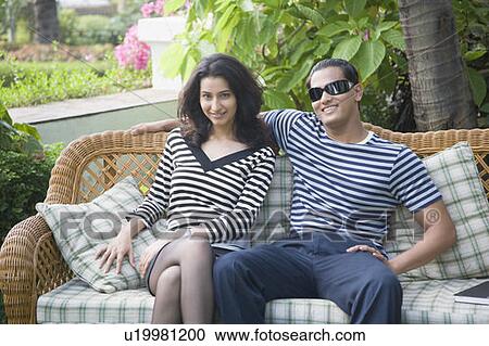 Young couple sitting on a couch and smiling View Large Photo Image Stock Image - Young couple sitting on a couch and smiling. Fotosearch