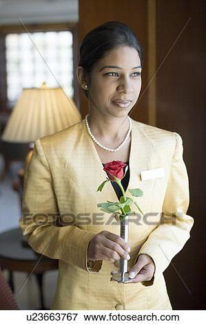 Close-up of a waitress holding a flower vase and smirking in a lobby View Large Photo Image Stock Photo - Close-up of a waitress holding a flower vase and smirking in a lobby. Fotosearch