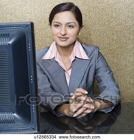 Female receptionist sitting at a hotel reception in front of a desktop PC View Large Photo Image Picture - Female receptionist sitting at a hotel reception in front of a desktop PC. Fotosearch