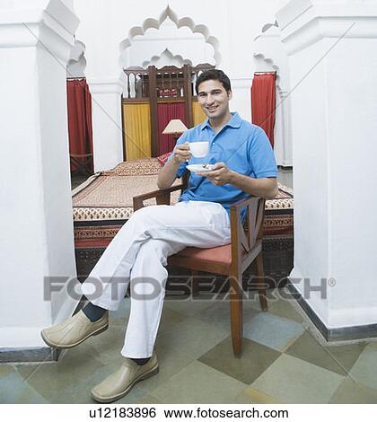 Portrait of a young man holding a cup of tea and smiling View Large Photo Image Stock Photograph - Portrait of a young man holding a cup of tea and smiling. Fotosearch