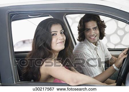 Stock Photo - Side profile of a young couple sitting inside a car and smiling. Fotosearch