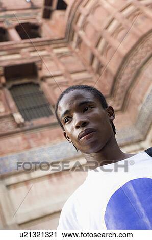 Stock Image - Low angle view of a young man looking away, Taj Mahal, Agra, Uttar Pradesh, India. Fotosearch