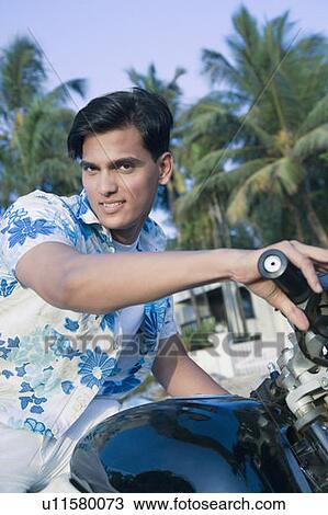 Stock Image - Portrait of a young man riding a motorcycle. Fotosearch