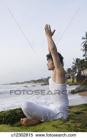 Stock Photography - Side profile of a young man meditating on the beach. Fotosearch