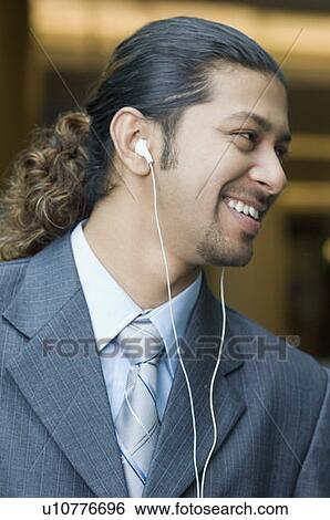 Close-up of a businessman listening to music and smiling View Large Photo Image Stock Photograph - Close-up of a businessman listening to music and smiling. Fotosearch